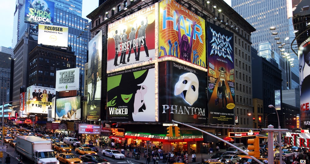 Times Square with billboard advertisements and cars in traffic.