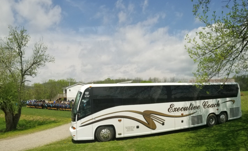 Executive Coach bus in a grassy area with blue skies